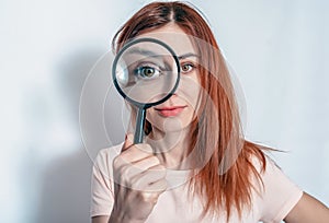 A woman's face through a magnifying glass. Long hair, big eyes. Research, choice concept