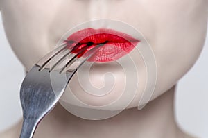 Woman's face with red lipstick and a fork