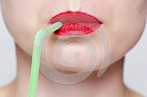 Woman's face with red lipstick and green straw