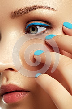 Woman`s face with vivid make-up and colorful nail polish