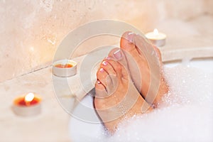 Woman`s feet in bath foam . Relaxation in hotel or spa