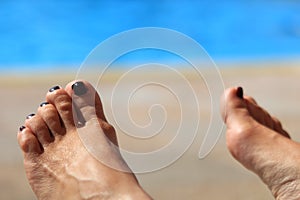 Woman's feet with blurred sunny swimming pool in background