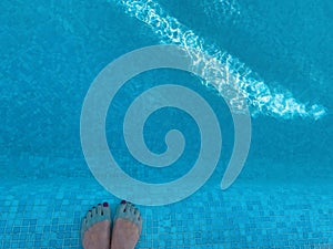 Woman`s feet legs in a swimming pool