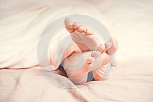 Woman`s feet peeking out from the blanket.