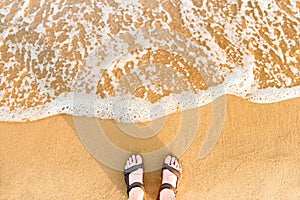 Woman`s feet in sandals on a beach sand