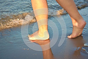 Woman& x27;s feet on the seashore at sunset