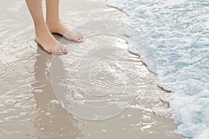 Woman`s feet standing in surf at the beach