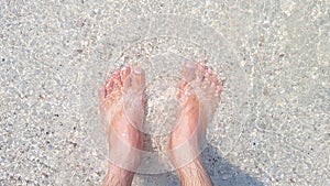 A woman's feet. She stands on a beach with beautiful sand and sea