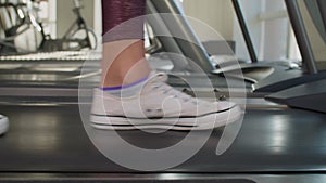 Woman's feet stepping on running treadmill machine