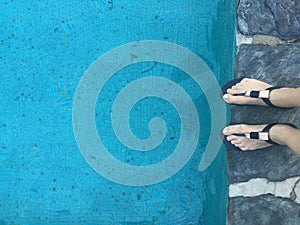 Woman`s feet on swimming pool ledge