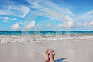 Woman`s feet on the tropical Caribbean beach. Ocean and blue sky