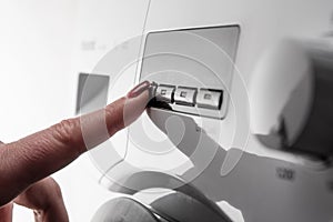 Woman`s finger with nail polish pushing start button on washing machine