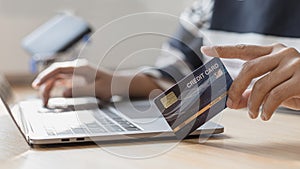 Woman`s finger presses a keyboard and holds a credit card to register for payment or online transactions