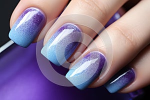 Woman\'s fingernails with blue and purple ombre colored nail polish design