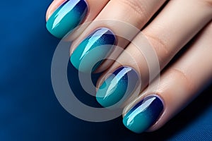 Woman\'s fingernails with dark blue and turquoise ombre colored nail polish design