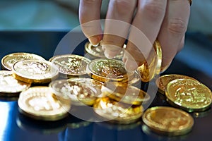 Woman's fingers holding gold coins