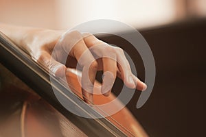 The woman's fingers on the strings of a cello
