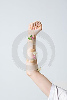 Woman`s fist as symbol of feminism with medical patches and flowers, concept photography for feminist blog or poster