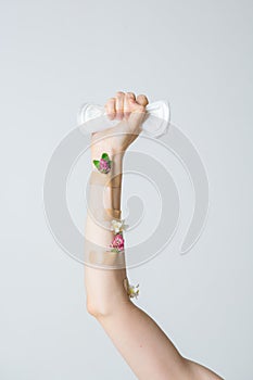 Woman`s fist as symbol of feminism with menstrual pad and flowers, concept photography for feminist blog or poster