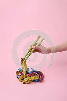 Woman`s hand with asparagus sticks is taking measuring tapes.