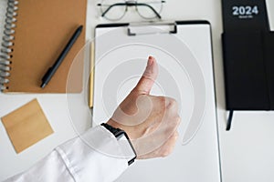 A woman\'s hand on the background of a desktop with notepads, paper, glasses and a calendar