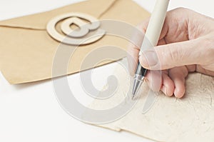 Woman`s hand with ballpoint pen  writing on old paper letter envelope, happy birthday congratulation card, personal note or