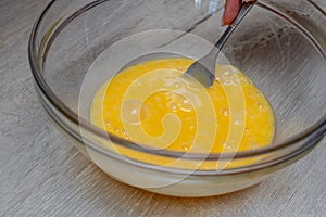 Woman`s hand beats eggs in a bowl