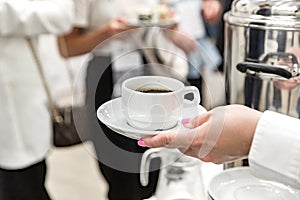 A woman\'s hand with a beautiful manicure holds a cup of coffee.