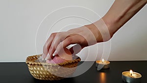 A woman`s hand with beautiful natural long nails takes a bath bomb from the basket. The atmosphere of relaxation and tranquility