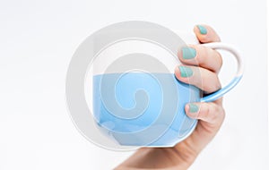 Woman's hand with blue nails holding a blue mug