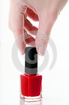 Woman's hand with a bottle of red nail polish