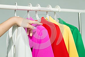 A woman's hand chooses clothes on a hanger on a white background