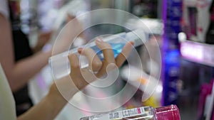 Woman`s hand choosing and buying a liquid makeup remover. A woman chooses a lotion for face care and cosmetics.