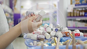 Woman`s hand choosing and buying a nail polish in a beauty shop. A woman holding cosmetics