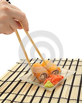 Woman`s hand with chopsticks and maki sushi