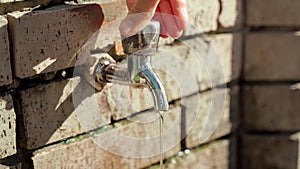 A woman's hand closes a street faucet. Urban infrastructure of cities. Handheld shooting.