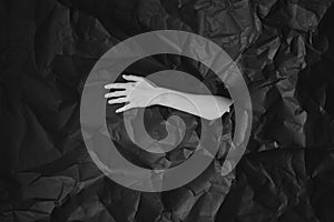 Woman`s hand comes out of hole in black crumpled paper, black and white concept photography for beauty blog or poster