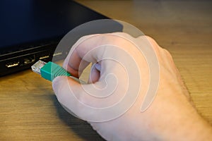 A woman's hand connects an RJ45 network connector to a laptop