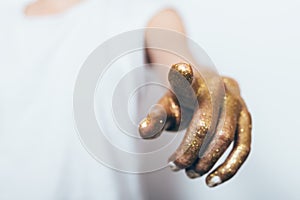 Woman`s hand covered with gold sequins pointing finger