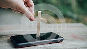 Woman`s hand with cross in screen mobile phone. Concept of hope, faith, christianity, religion, church online