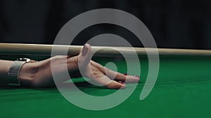 A woman's hand with cue aiming on billiard ball at green table