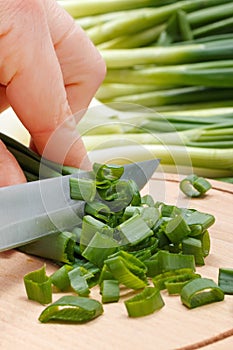 Woman's hand cutting green onion