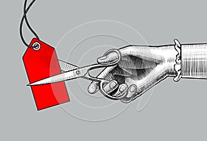 Woman`s hand cutting a red label with scissors.