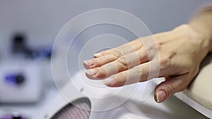 A woman's hand demonstrates uncoated nails prepared for manicure