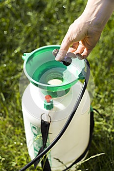 A woman`s hand doses the amount of the agent by pouring into the sprayer.
