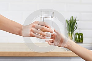 Woman`s hand gives a glass of purified water to her child. Concept purification of water