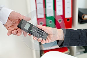 Woman's hand giving a phone to her colleague