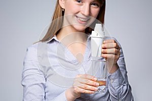 The woman& x27;s hand with a glass of purified water. The concept of water purification through the mineral filter on gray