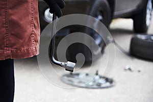 Woman`s hand in a glove with a key for mounting a wheel for a car
