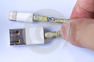 Woman`s hand hold Damaged white usb cable plug and micro usb plug or Old Smart Phone Charger Cable broken on white acrylic